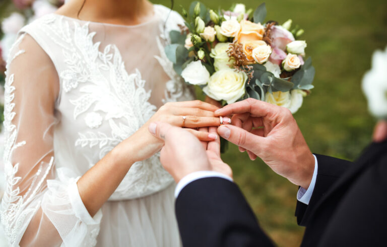 Wedding engagement rings. Groom put a ring on finger of his lovely wife. Concept wedding details. Happy family