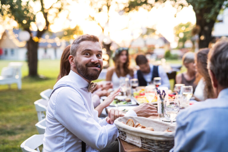 Guests eating at the wedding reception outside in the backyard