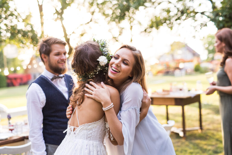 Young girl congratulating bride and groom at wedding reception in the backyard